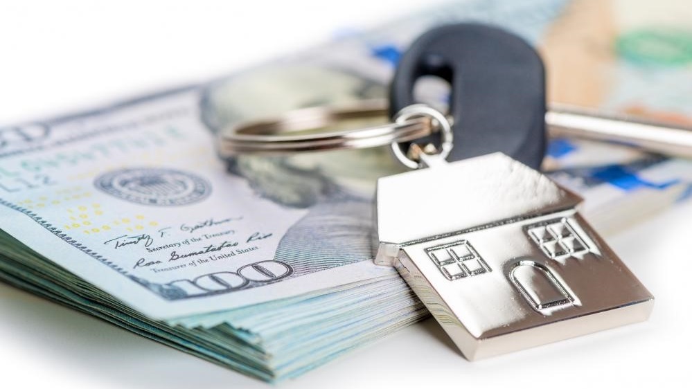 home-keys-sell-money House keys on a pile of US Dollars